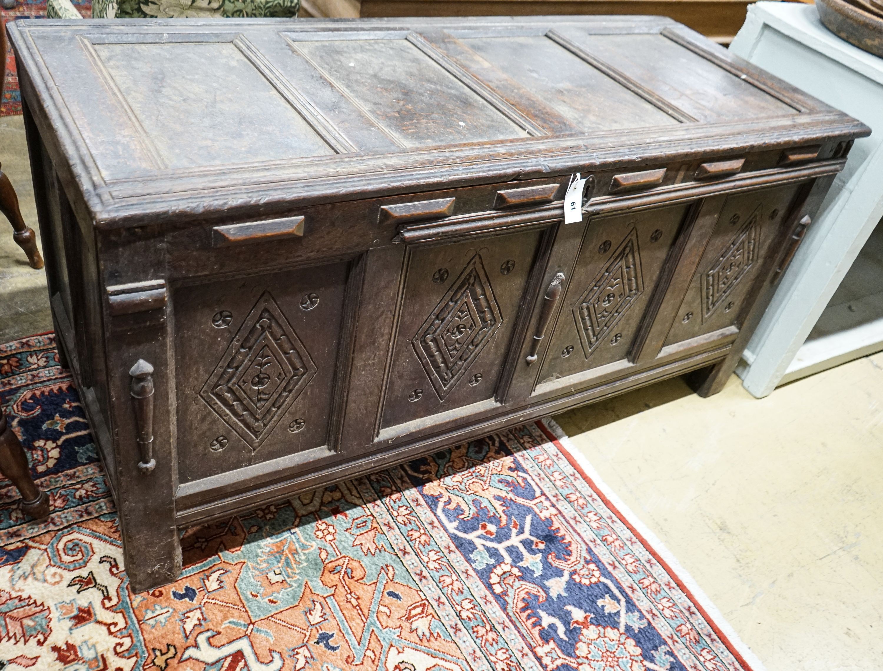 An early 18th century oak coffer, with four panel top and later carved and applied decoration, width 152cm, depth 63cm, height 74cm